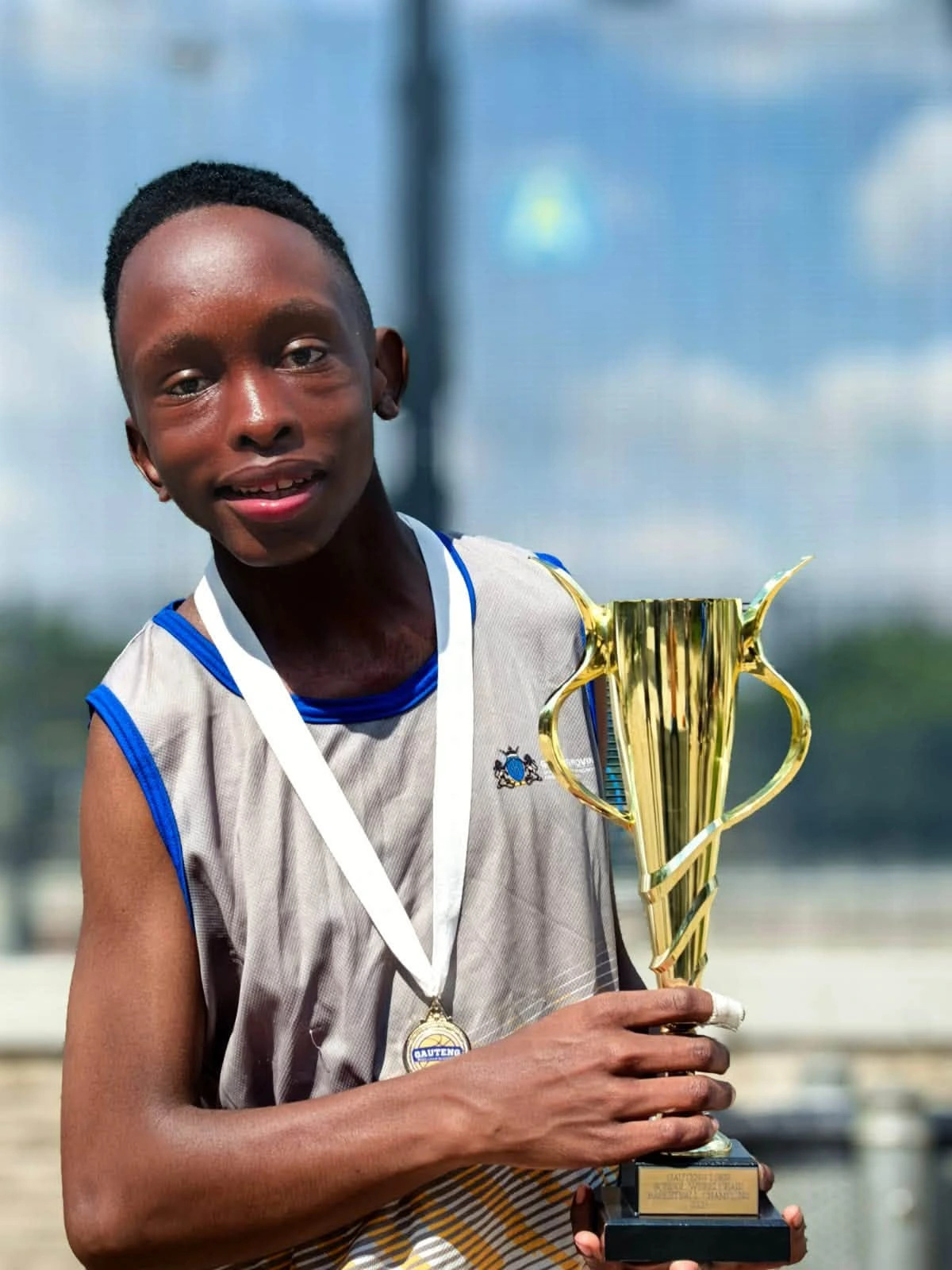 A basketball player holding the championship trophy. Photo: Ithembelihle LSEN School. Posted 2026-10-13.